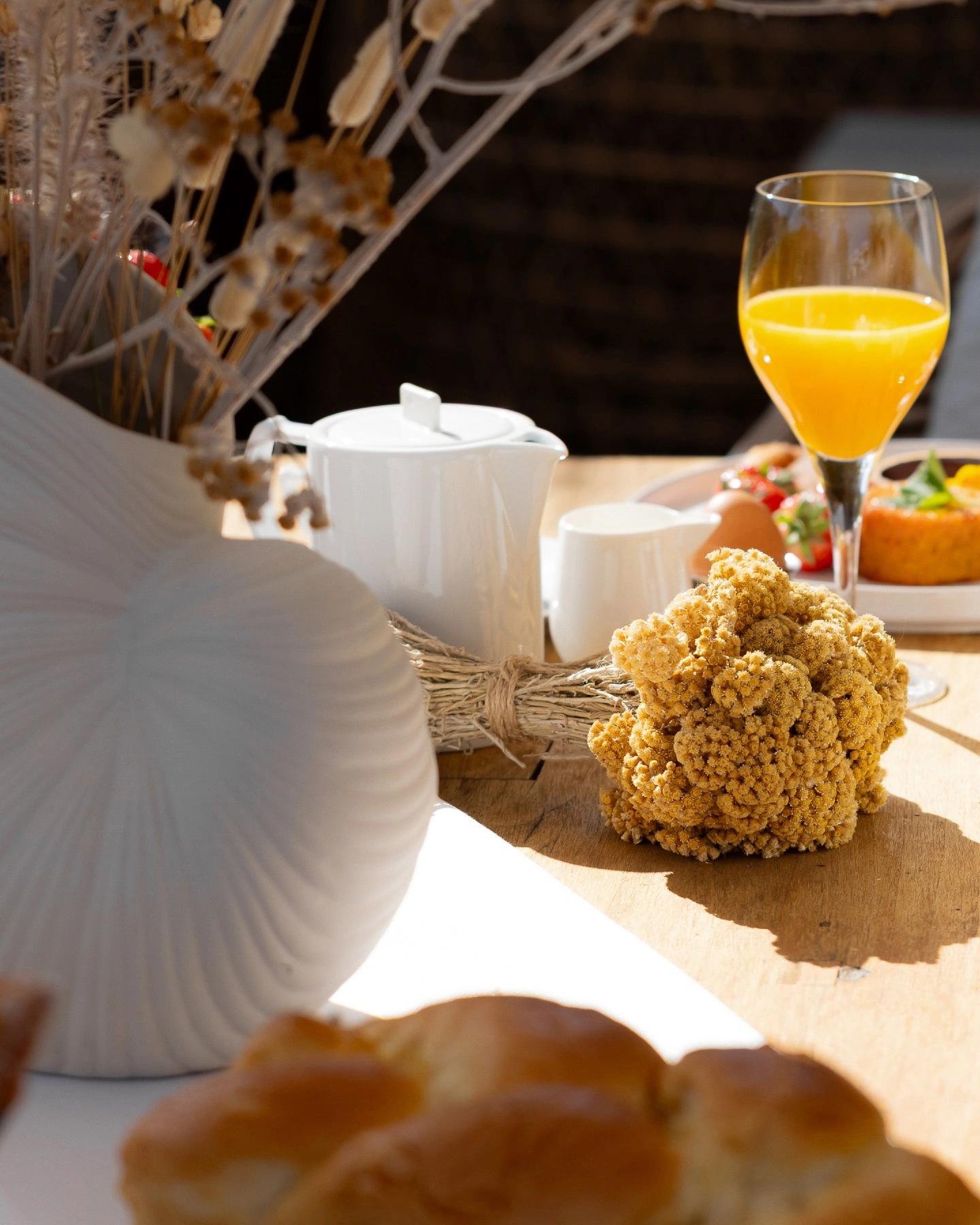 Petit-déjeuner servi au soleil : brioche, jus d'orange et fleurs séchées